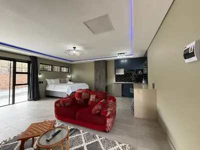 a living room with a red couch and a bed at JuaMtoto guesthouse in Pretoria