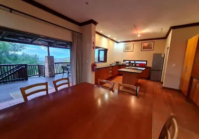 a kitchen and dining room with a table and a balcony at Valley View Elements 4 Bedroom in Warmbaths