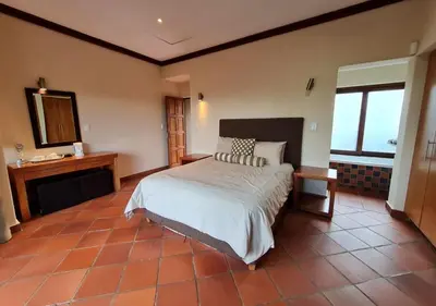 a large bedroom with a bed and a mirror at Valley View Elements 4 Bedroom in Warmbaths