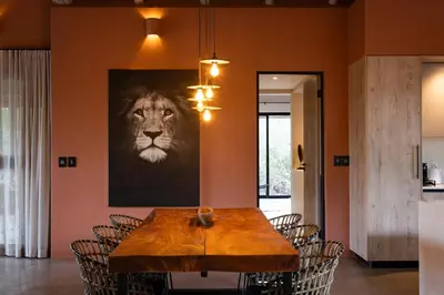 a dining room with a table with a lion picture on the wall at Villa White Lion - Luxurious Villa nearby Kruger in Hoedspruit