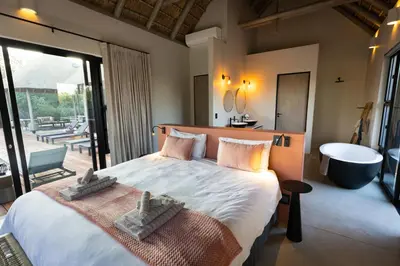 a bedroom with a large bed and a bath tub at Villa White Lion - Luxurious Villa nearby Kruger in Hoedspruit