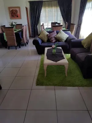 a living room with couches and a table on a green rug at Ramandire B&B in Witbank