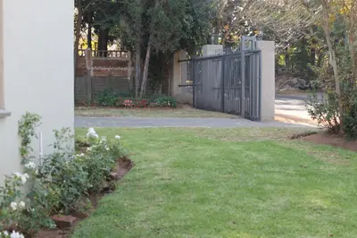 a driveway with a gate and a yard with flowers at Ramandire B&B in Witbank