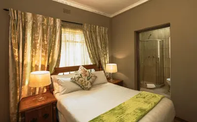 a bedroom with a bed with two lamps and a window at Ramandire B&B in Witbank
