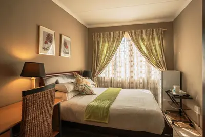 a bedroom with a large bed and a window at Ramandire B&B in Witbank