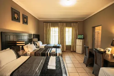 a hotel room with two beds and a desk at Ramandire B&B in Witbank