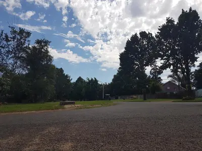 an empty street with trees and a cloudy sky at Ramandire B&B in Witbank