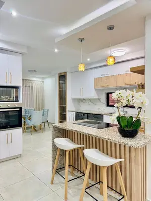 a kitchen with white cabinets and a counter with stools at Zaidi Luxury Home in Secunda
