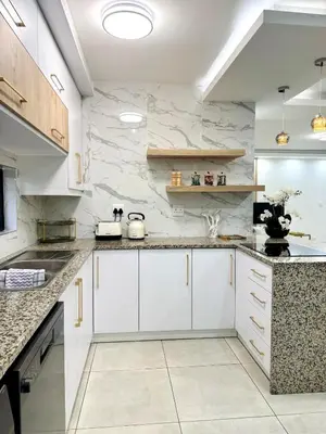 a kitchen with white cabinets and marble walls at Zaidi Luxury Home in Secunda