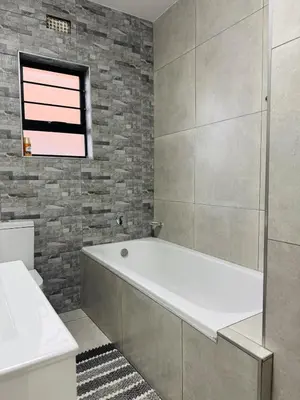 a bathroom with a bath tub and a window at Zaidi Luxury Home in Secunda