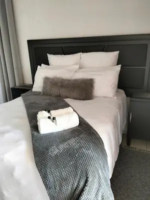 a large bed with white sheets and a black headboard at 20 on Middle in Polokwane