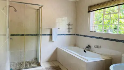 a bathroom with a shower and a tub and a sink at Yvee Guesthouse in Hazyview
