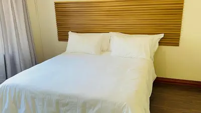 a bed with white sheets and pillows in a room at Home 11 Strydom in Nelspruit