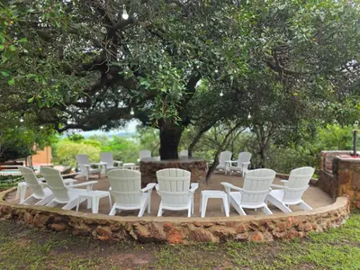 a group of white chairs sitting under a tree at Rocky Mountain Holiday Home in Hartbeespoort