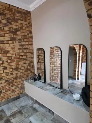 a room with three mirrors on a brick wall at Rocky Mountain Holiday Home in Hartbeespoort