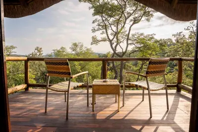two chairs on a deck with a view of trees at Tshwene Lodge in Welgevonden Game Reserve