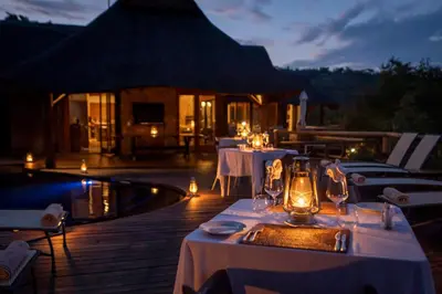 a restaurant with white tables and chairs next to a pool at Tshwene Lodge in Welgevonden Game Reserve