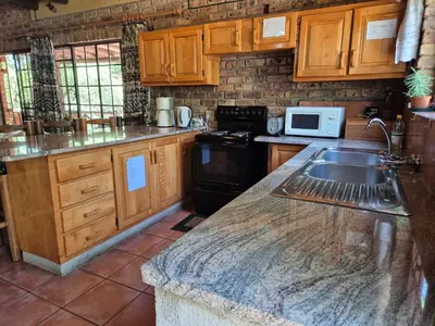 a kitchen with wooden cabinets and a sink at Rafikis Safari at Kruger in Marloth Park