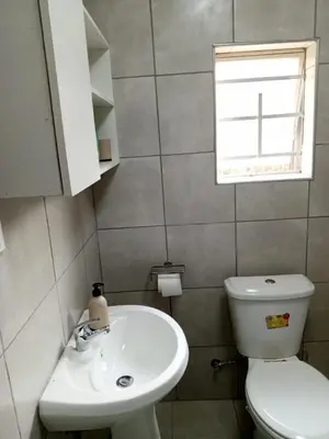 a bathroom with a toilet and a sink and a window at Millenium Manor Executive Homes in Centurion