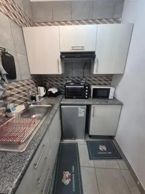 a small kitchen with white cabinets and a sink at Millenium Manor Executive Homes in Centurion