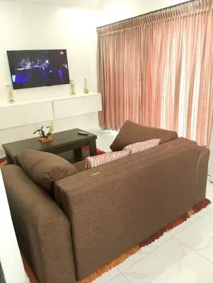 a living room with a brown couch and a tv at Millenium Manor Executive Homes in Centurion