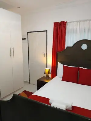 a bedroom with a bed with red pillows and a mirror at Millenium Manor Executive Homes in Centurion