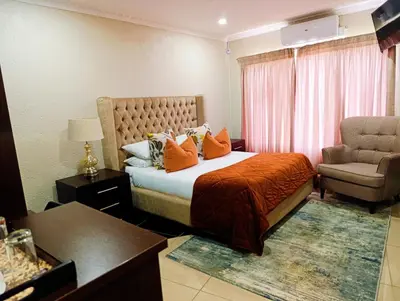 a hotel room with a bed and a chair at Elephant villa 5 bedroom in Nelspruit