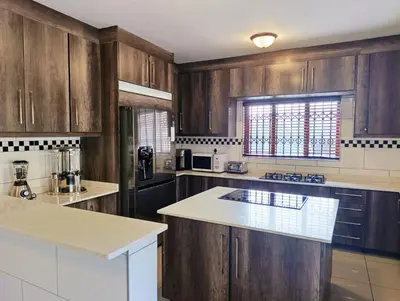 a kitchen with wooden cabinets and a white counter top at Elephant villa 5 bedroom in Nelspruit