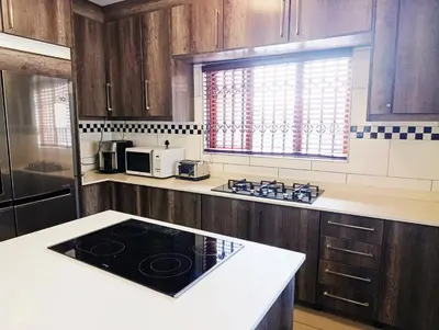 a kitchen with wooden cabinets and a black counter top at Elephant villa 5 bedroom in Nelspruit