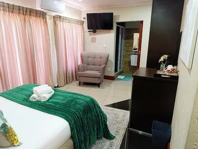 a hotel room with a bed and a chair at Elephant villa 5 bedroom in Nelspruit