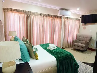 a bedroom with a bed with a chair and a couch at Elephant villa 5 bedroom in Nelspruit