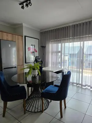 a dining room with a glass table and blue chairs at Views at The Blyde in Pretoria