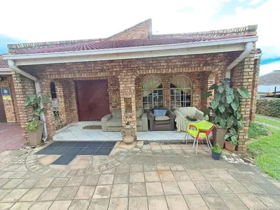 a brick house with a patio and a yellow chair at Simunye Retreat in White River