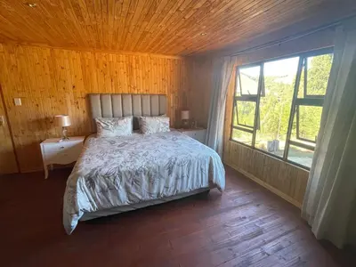 a bedroom with a bed and a large window at Shyalongubo dam cabin in Barberton