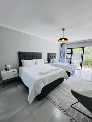 a bedroom with two beds and a large window at Nelspruit Modern Apartment #1 - Self Check-In in Nelspruit