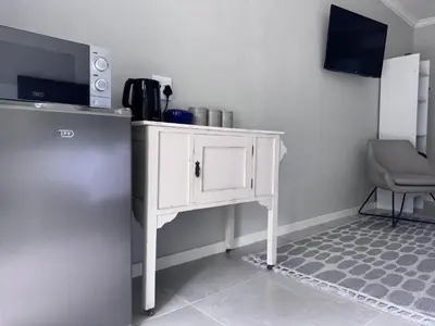 a white cabinet in a room with a chair at Nelspruit Modern Apartment #1 - Self Check-In in Nelspruit