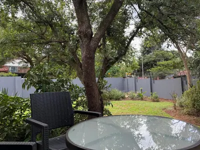 a table and chairs and a tree in a yard at Nelspruit Modern Apartment #1 - Self Check-In in Nelspruit
