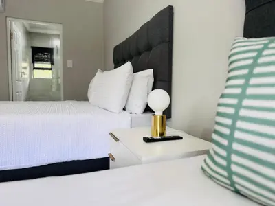 a bedroom with a bed and a lamp on a night stand at Nelspruit Modern Apartment #1 - Self Check-In in Nelspruit