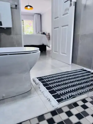 a bathroom with a toilet and a black and white floor at Nelspruit Modern Apartment #1 - Self Check-In in Nelspruit