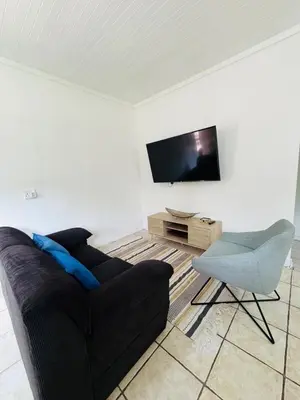 a living room with a black couch and a chair at Nartjie - Apartment #3 in Nelspruit