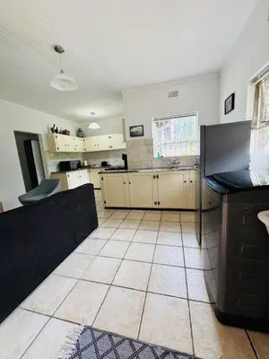 a kitchen with white cabinets and a tile floor at Nartjie - Apartment #3 in Nelspruit