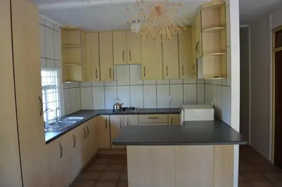 a kitchen with wooden cabinets and a black counter top at Guesthouse in the Waterberg in Ouklip