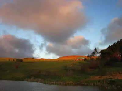 a view of a field with a pond and a barn at Kwaggaskop Game Farm - near Dullstroom in Belfast