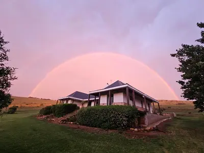 a rainbow in the sky above a house at Kwaggaskop Game Farm - near Dullstroom in Belfast