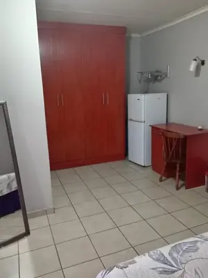 a kitchen with red cabinets and a table and refrigerator at Simekhona Guest House in Aangewysd