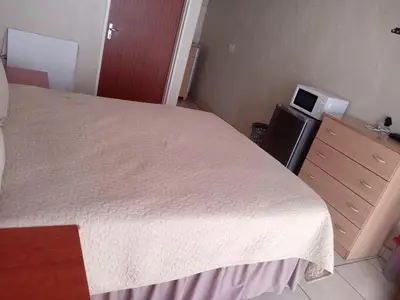 a bedroom with a bed with a white bedspread and a dresser at Simekhona Guest House in Aangewysd