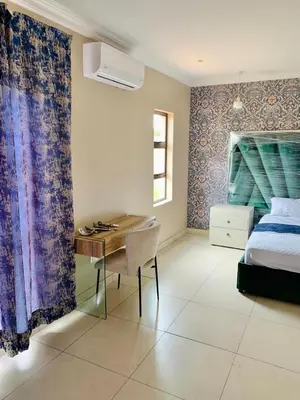 a bedroom with a desk and a bed and a bed and a desk at Hlako Lodge in Ga-Tisana