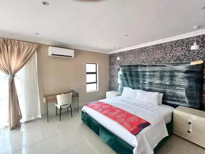 a bedroom with a bed and a table and a window at Hlako Lodge in Ga-Tisana