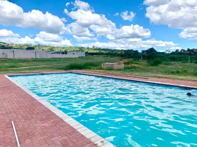 a swimming pool with blue water in a yard at Hlako Lodge in Ga-Tisana