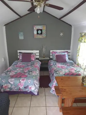 a bedroom with two beds and a wooden table at Chalet 1 Camping Style at Cynthias Country Farmstay Outside bathroom in Hartbeespoort
